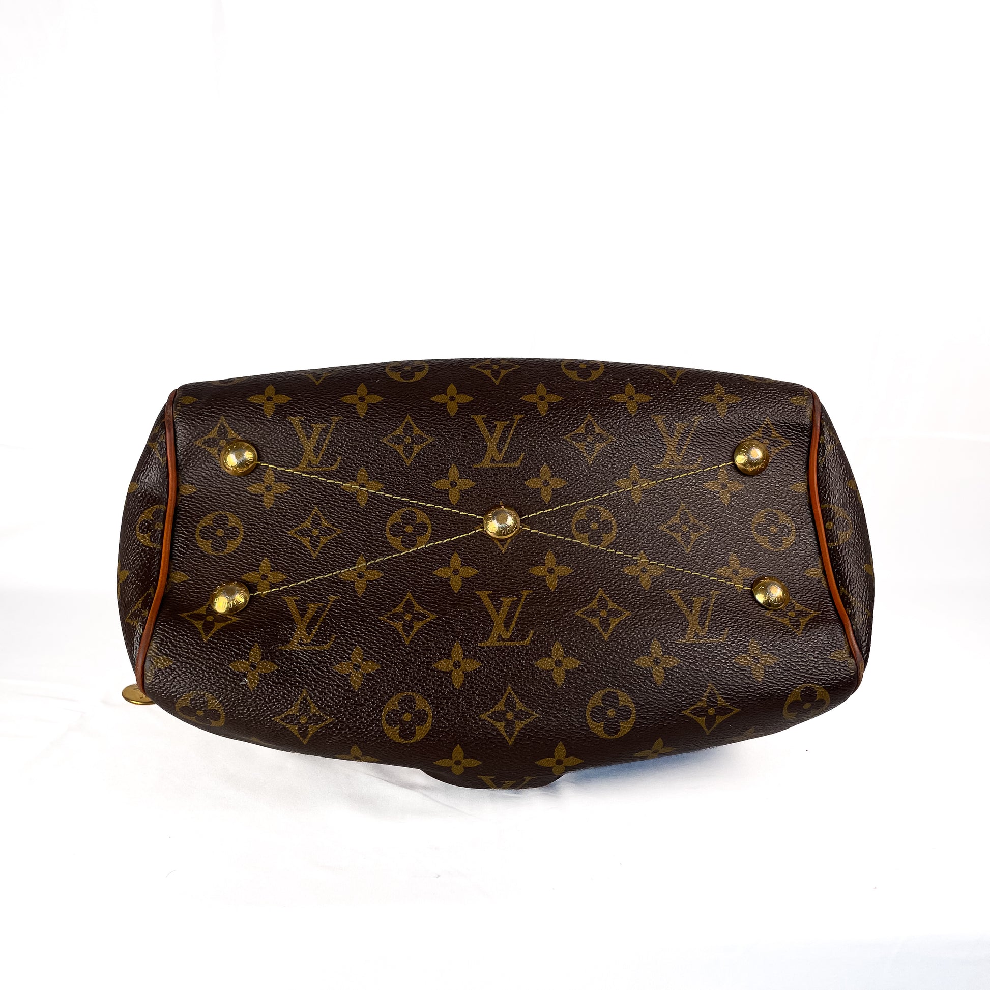 Louis Vuitton monogram canvas shoulder bag shown from the bottom, featuring the classic brown and gold LV pattern with gold-tone metal studs on a white background.
